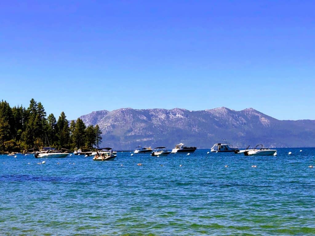 Scenic view of Lake Tahoe with boats in the water and mountains and trees in the background