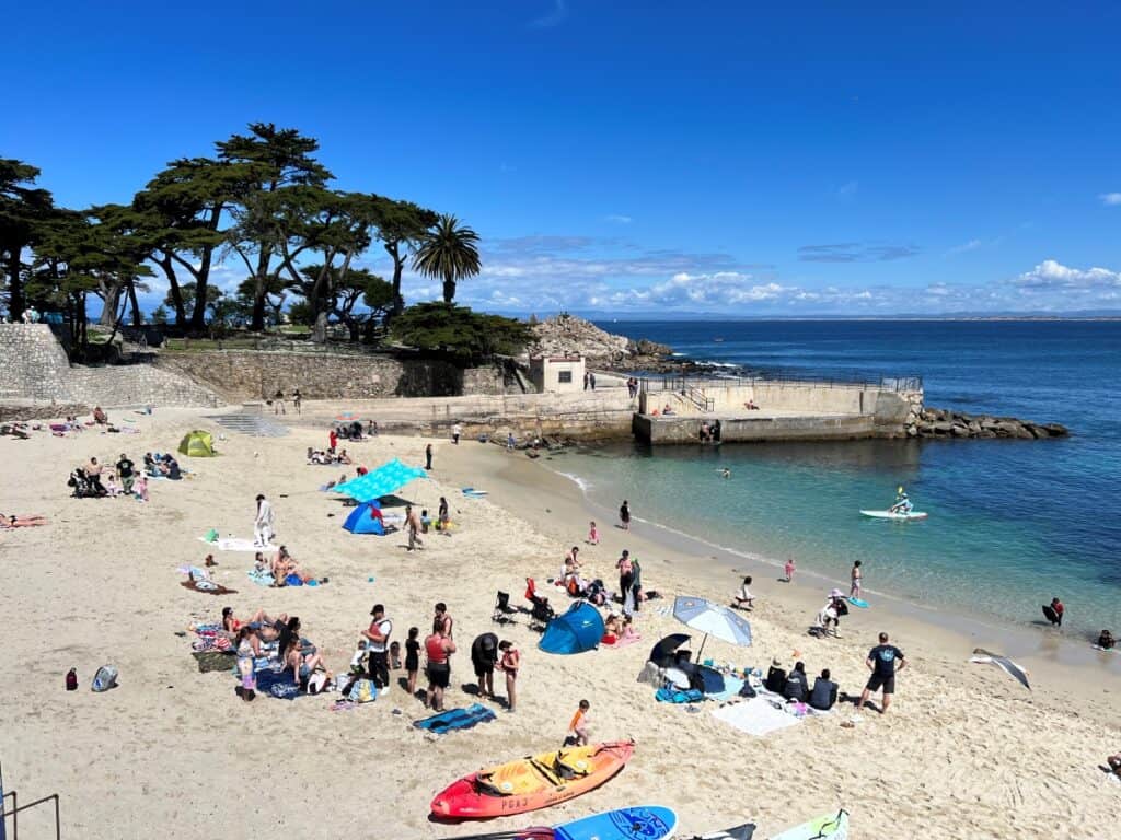 a sandy beach with people lounging and several colorful kayaks and ocean views in the backdrop