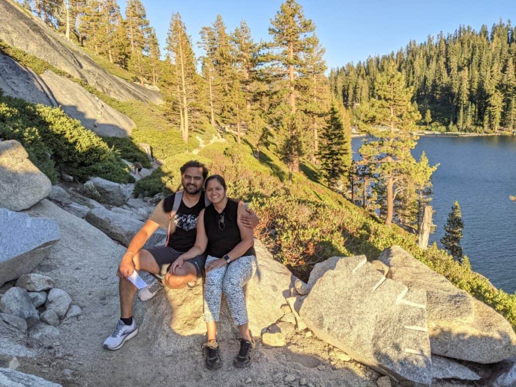 A couple posing sitting on a boulder at a hiking trail