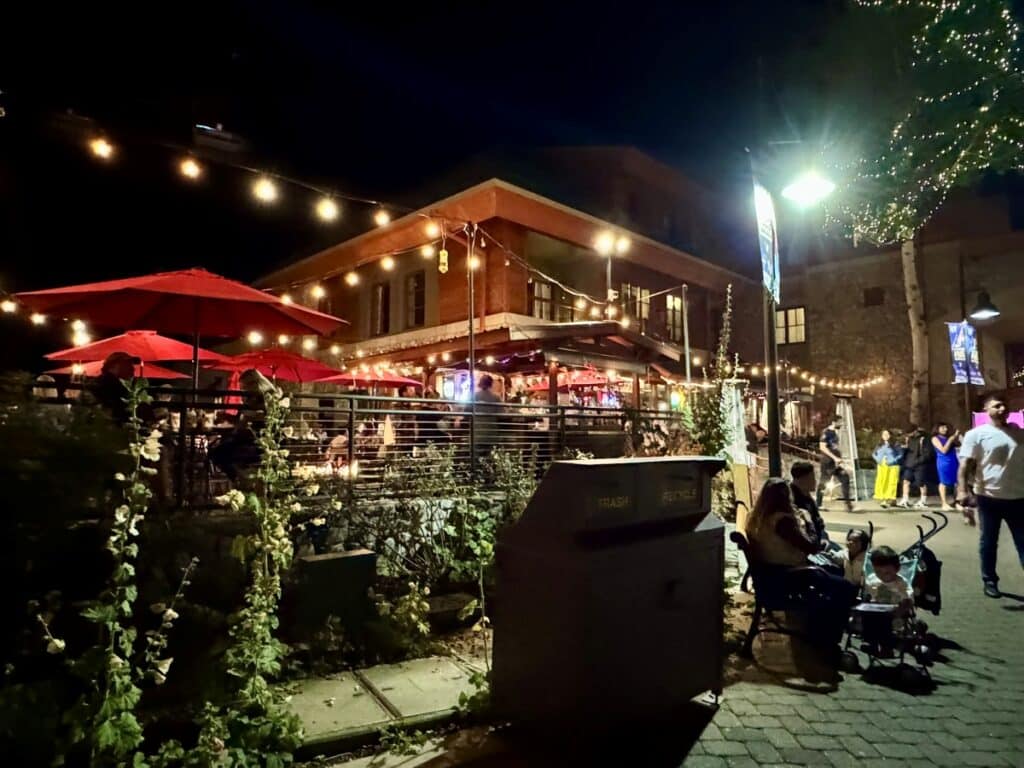 A well lit village square with shops and people