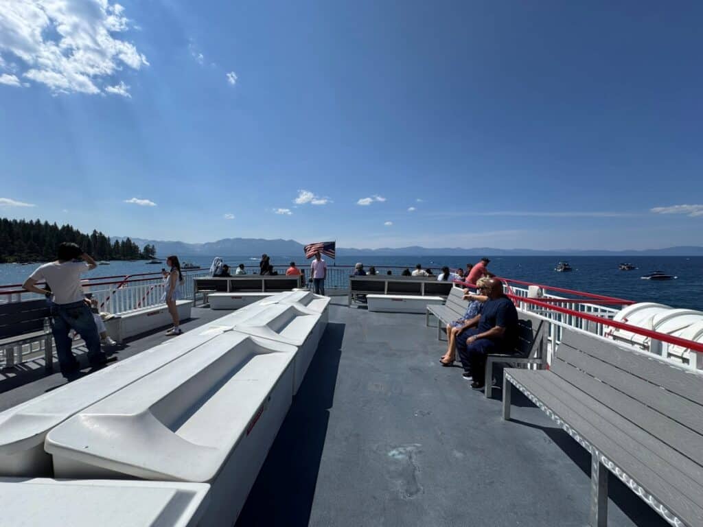 An open deck on a boat with bench seating and views of water and mountains