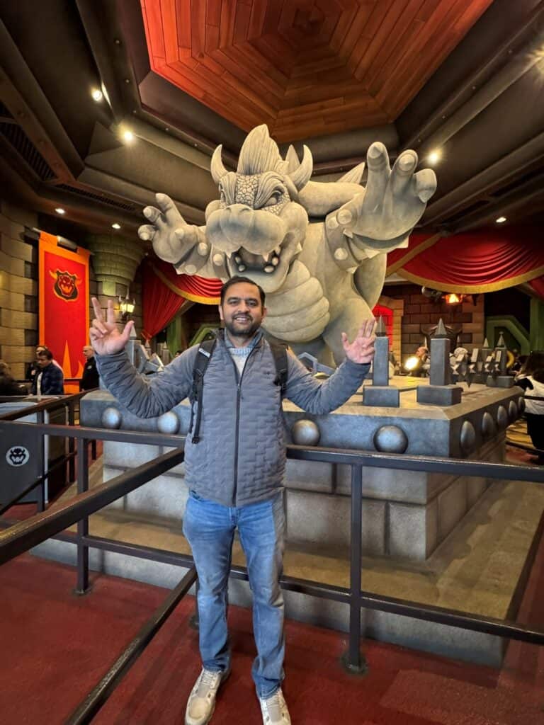 A guy posing in front of Bowser's statue in Mario Kart ride